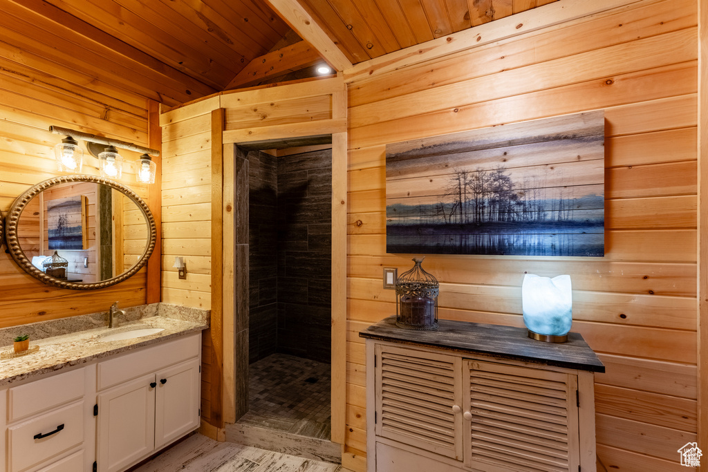 Bathroom with beam ceiling, vanity, wood walls, hardwood / wood-style floors, and wood ceiling