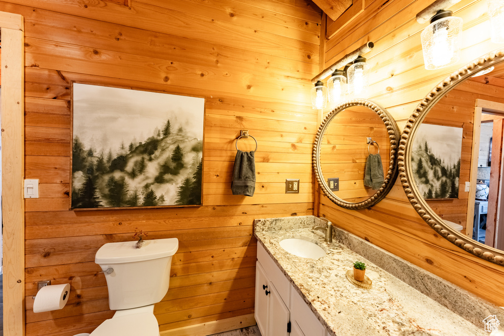 Bathroom with wood walls, toilet, and vanity