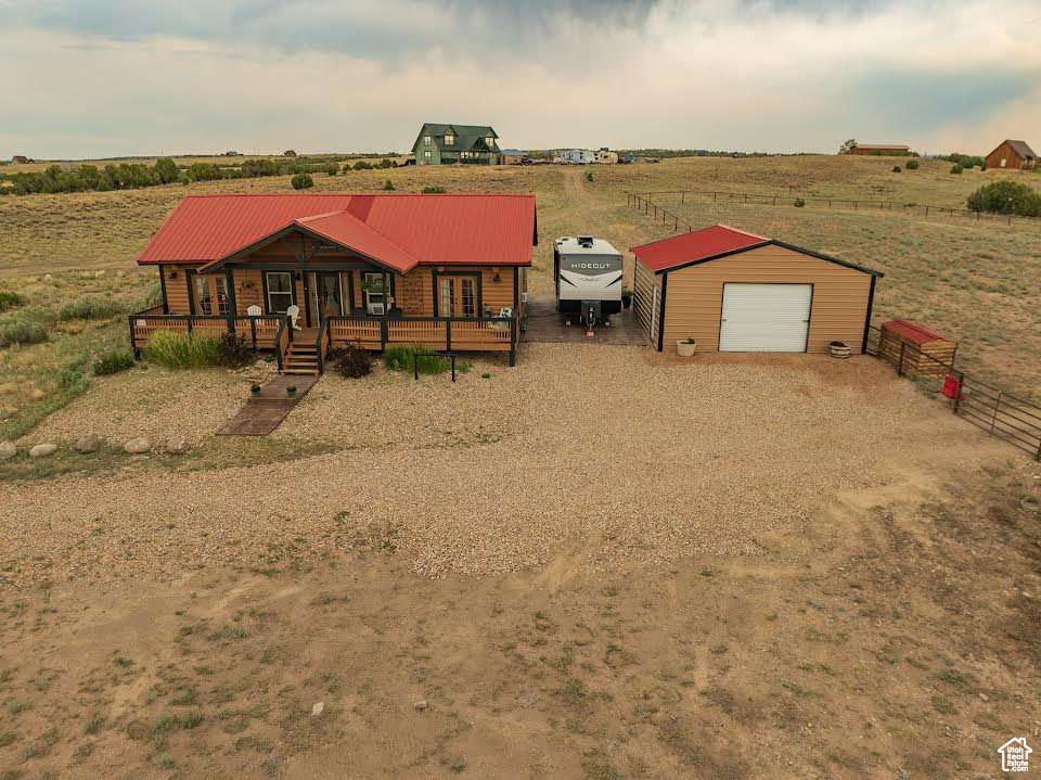 View of front facade with a garage, a porch, an outbuilding, and a rural view