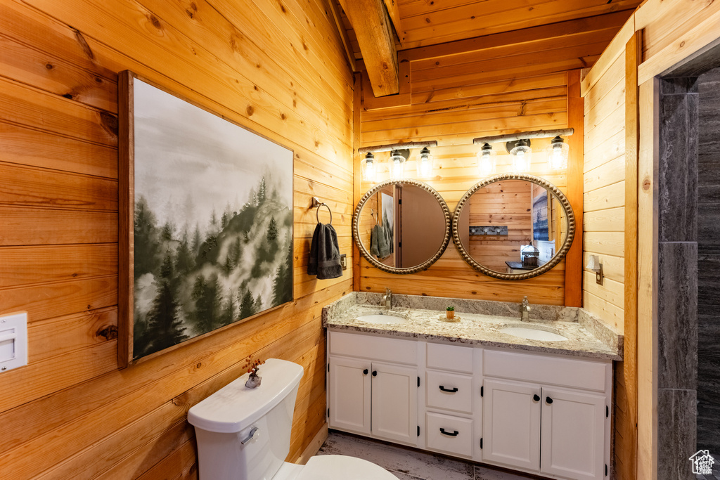 Bathroom with dual bowl vanity, wooden ceiling, wooden walls, and toilet