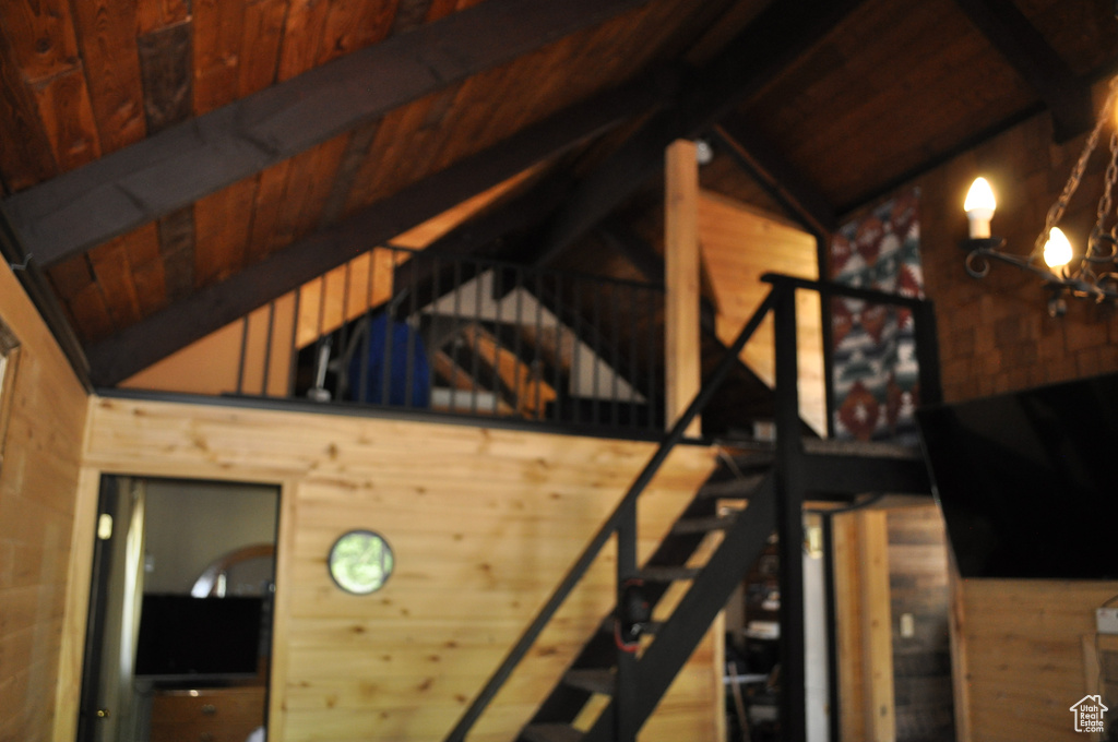 Interior space with wooden ceiling, vaulted ceiling with beams, a chandelier, and wood walls