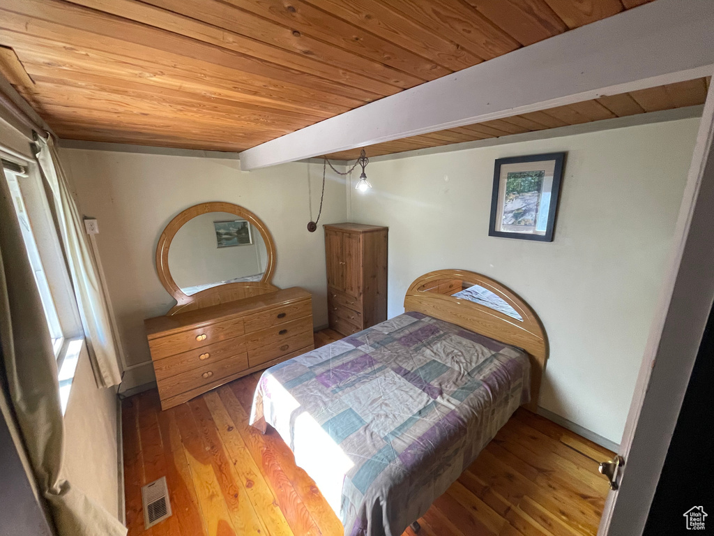 Bedroom featuring beamed ceiling, light hardwood / wood-style flooring, and wooden ceiling