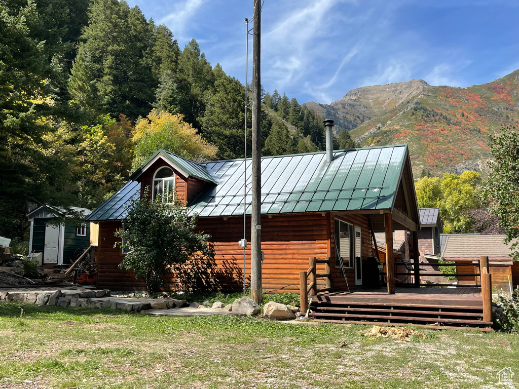 View of front facade with a front yard, a deck with mountain view, and an outbuilding