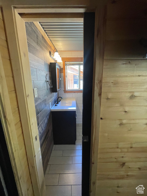 Hallway featuring wood walls, light tile patterned floors, and sink