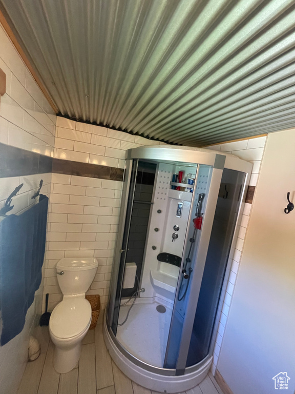 Bathroom with tile walls, toilet, and an enclosed shower