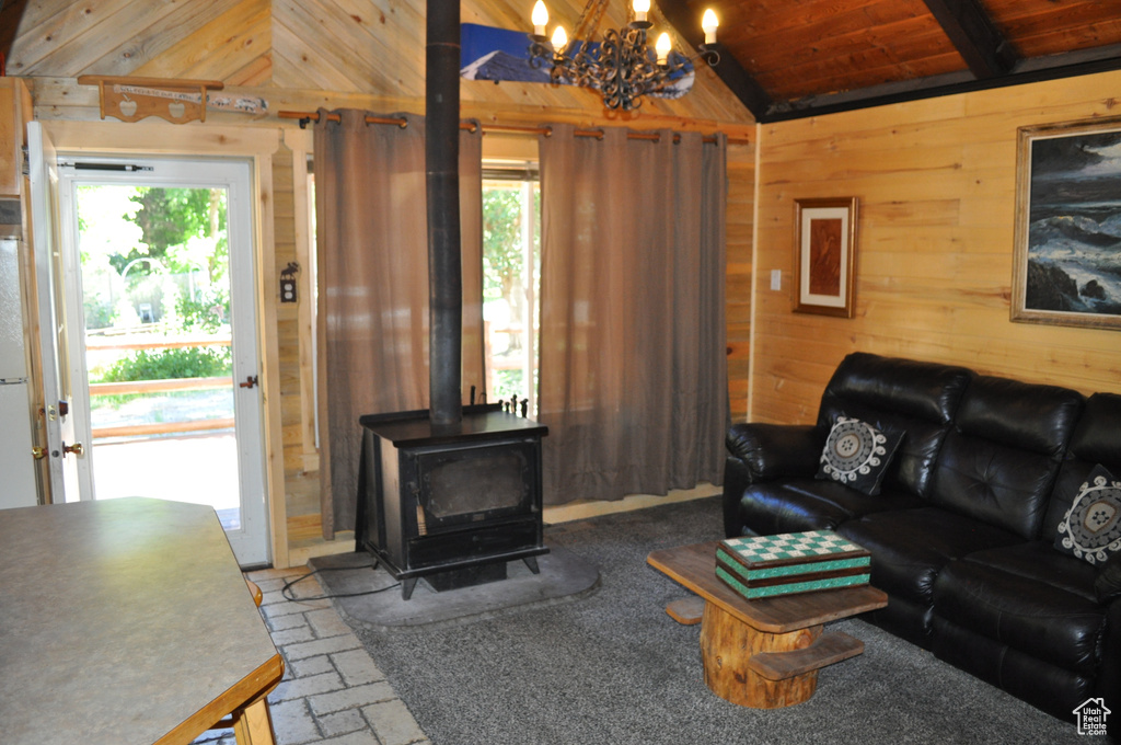 Living room with wooden walls, lofted ceiling, a healthy amount of sunlight, and a wood stove