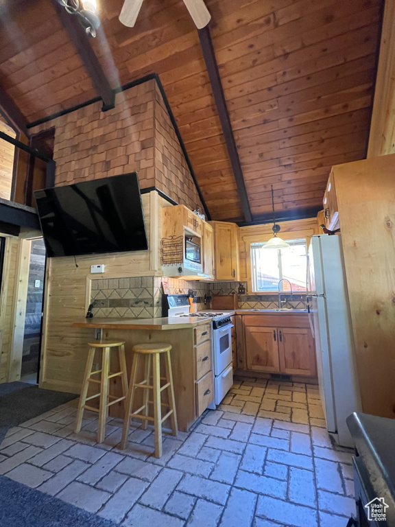 Kitchen with ceiling fan, wood ceiling, sink, white appliances, and a breakfast bar area