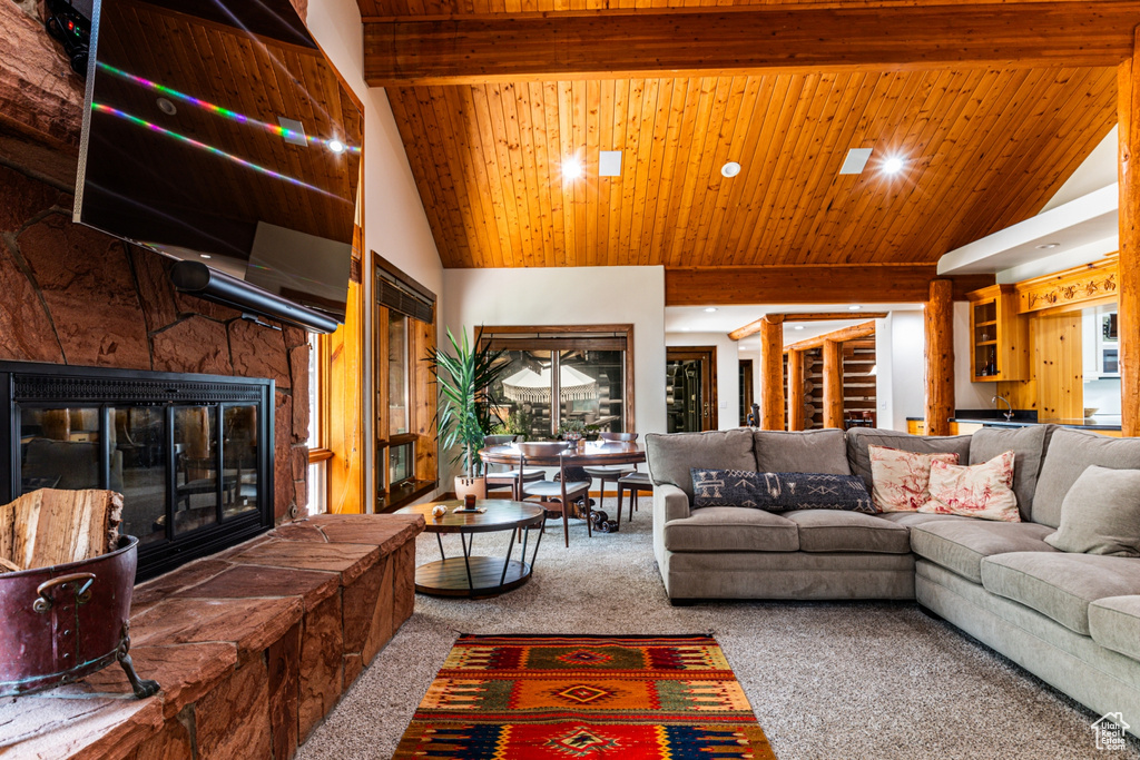 Living room with a stone fireplace, wood ceiling, carpet, high vaulted ceiling, and beam ceiling