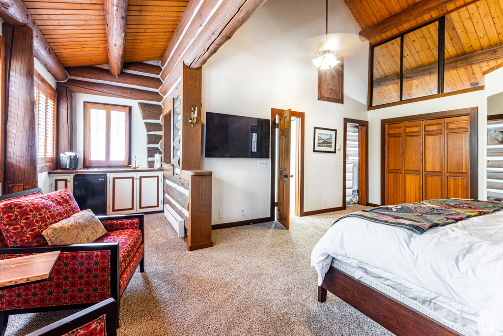 Bedroom with fridge, lofted ceiling with beams, wooden ceiling, and light colored carpet