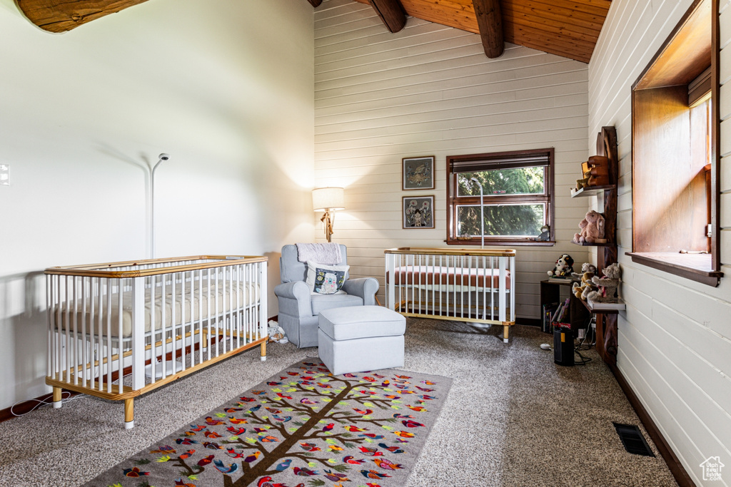 Bedroom featuring beam ceiling, wooden ceiling, a crib, high vaulted ceiling, and carpet floors