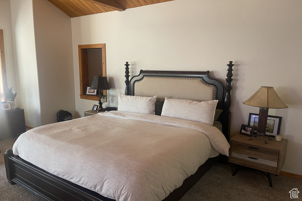 Carpeted bedroom with vaulted ceiling with beams and wood ceiling