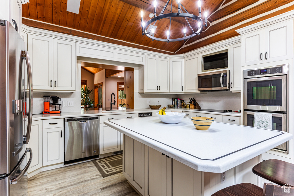 Kitchen with wooden ceiling, stainless steel appliances, a kitchen island, light hardwood / wood-style flooring, and a kitchen bar