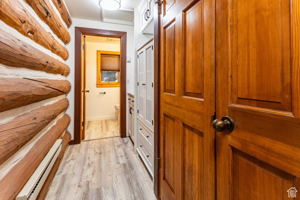 Corridor featuring baseboard heating, crown molding, and light wood-type flooring