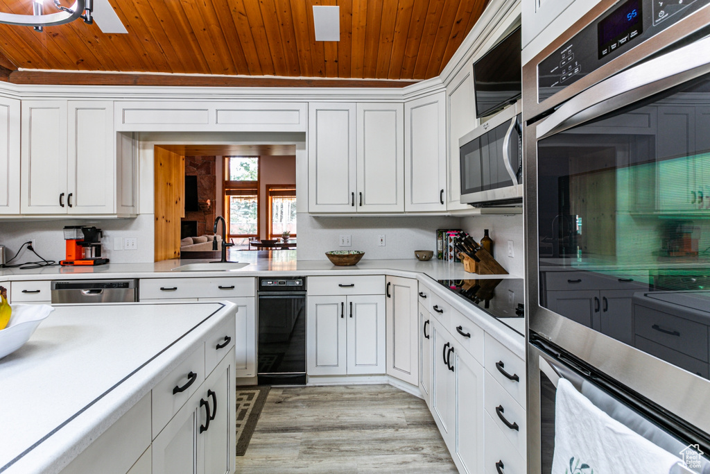 Kitchen featuring wood ceiling, white cabinetry, light hardwood / wood-style floors, stainless steel appliances, and sink