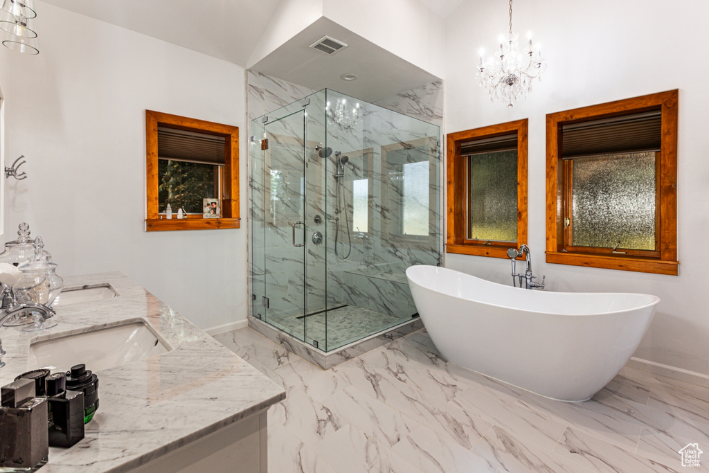 Bathroom with lofted ceiling, shower with separate bathtub, tile patterned floors, an inviting chandelier, and dual bowl vanity