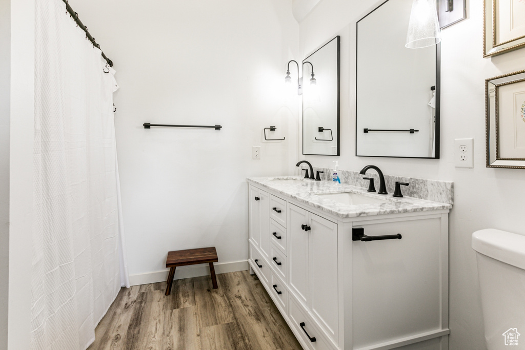 Bathroom with double sink vanity, hardwood / wood-style flooring, and toilet