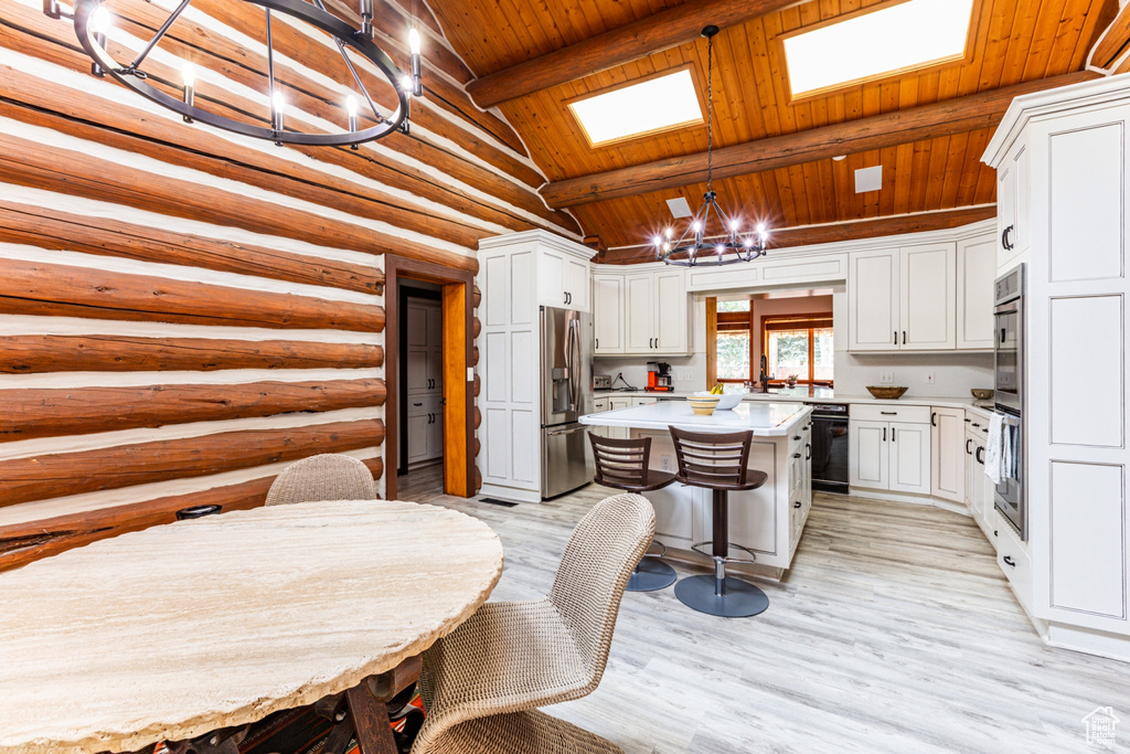 Kitchen with light hardwood / wood-style flooring, wooden ceiling, pendant lighting, a center island, and log walls