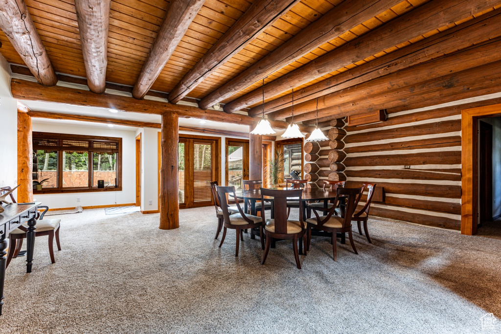 Carpeted dining room featuring log walls, beam ceiling, and wooden ceiling