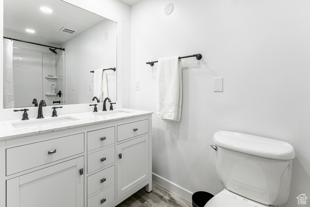 Bathroom featuring toilet, dual bowl vanity, and hardwood / wood-style flooring