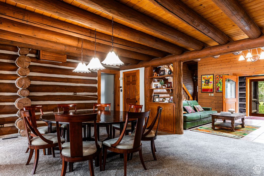 Carpeted dining space featuring a chandelier, beamed ceiling, wooden walls, and wood ceiling