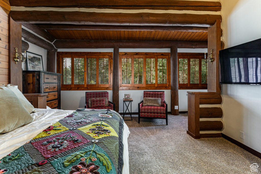 Carpeted bedroom with beamed ceiling, wood ceiling, and multiple windows