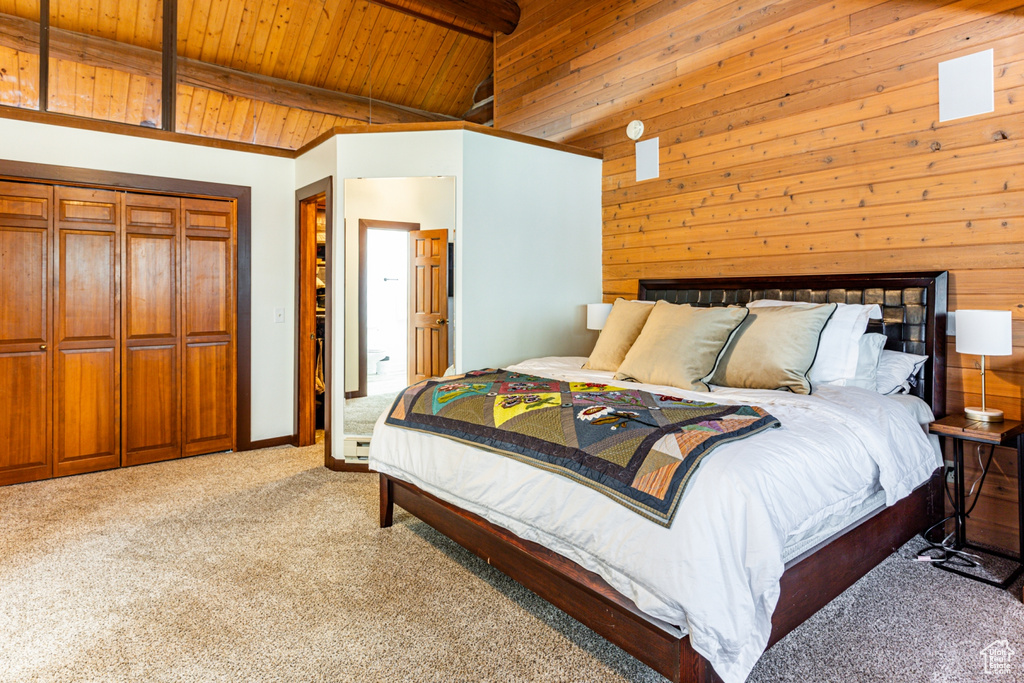 Carpeted bedroom featuring wood walls, vaulted ceiling with beams, and wood ceiling