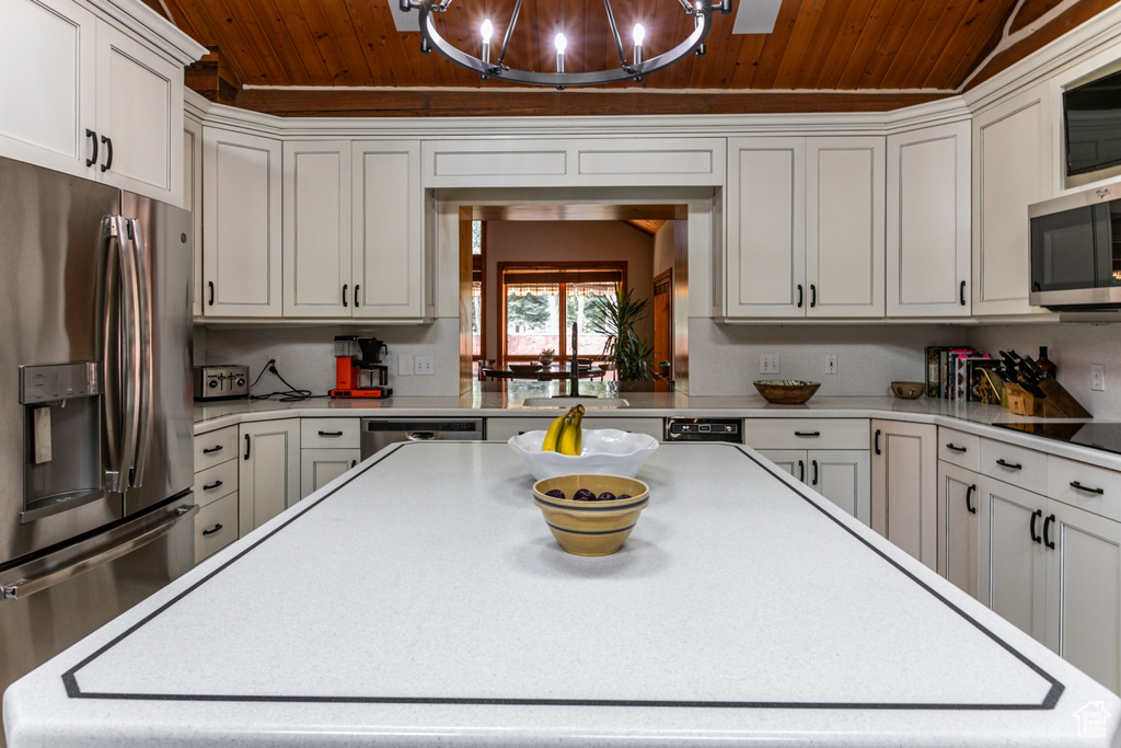 Kitchen with wooden ceiling, stainless steel appliances, an inviting chandelier, and white cabinetry