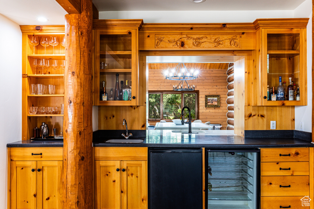 Bar featuring a notable chandelier, sink, black dishwasher, and beverage cooler