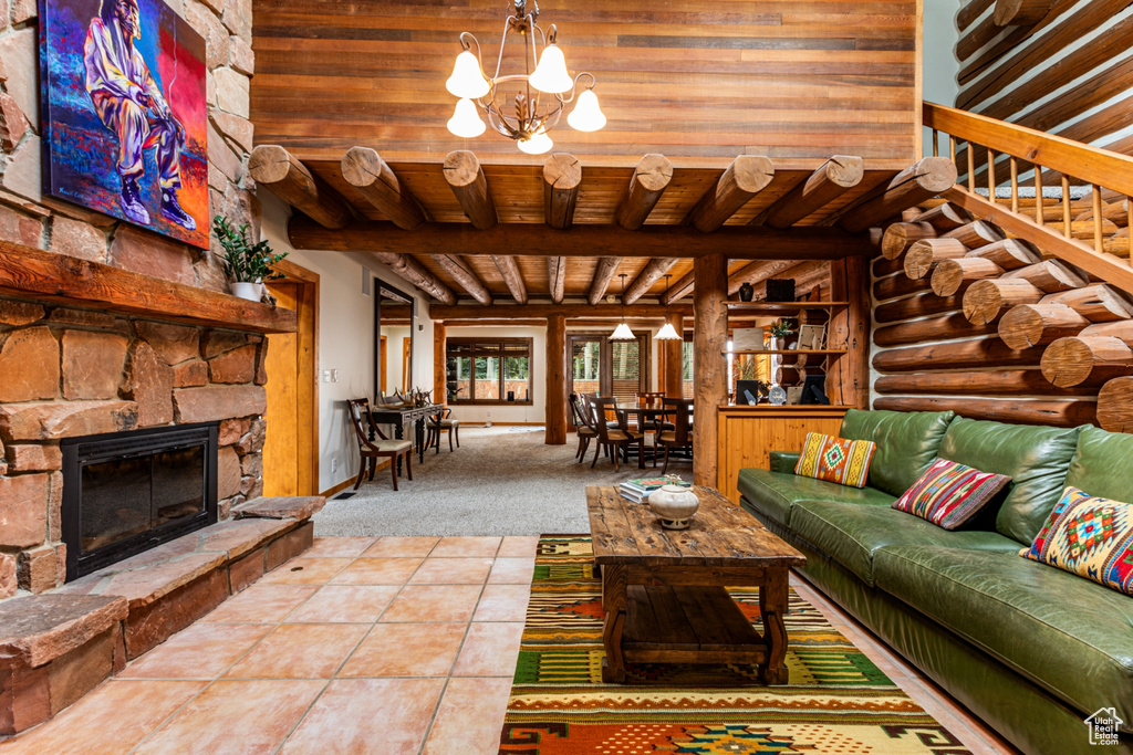 Living room featuring a stone fireplace, wood ceiling, a notable chandelier, beam ceiling, and tile patterned flooring