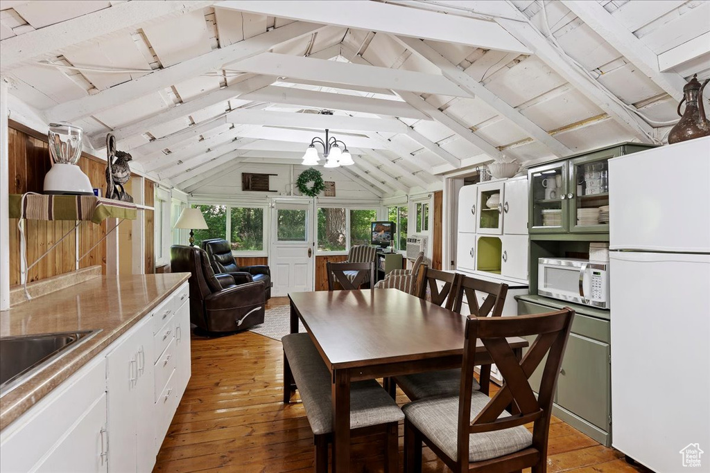 Dining area featuring light hardwood / wood-style flooring, an inviting chandelier, and lofted ceiling