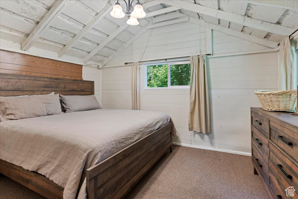 Bedroom with lofted ceiling with beams, an inviting chandelier, wood walls, dark colored carpet, and wooden ceiling