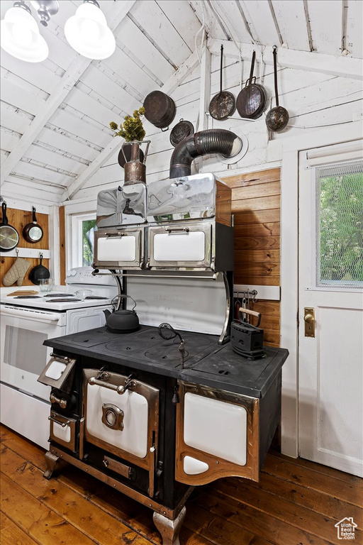 Details featuring wooden walls, hardwood / wood-style flooring, double oven range, and beam ceiling