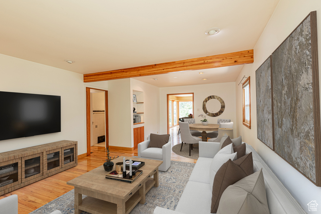 Living room with beam ceiling, built in features, and light hardwood / wood-style floors