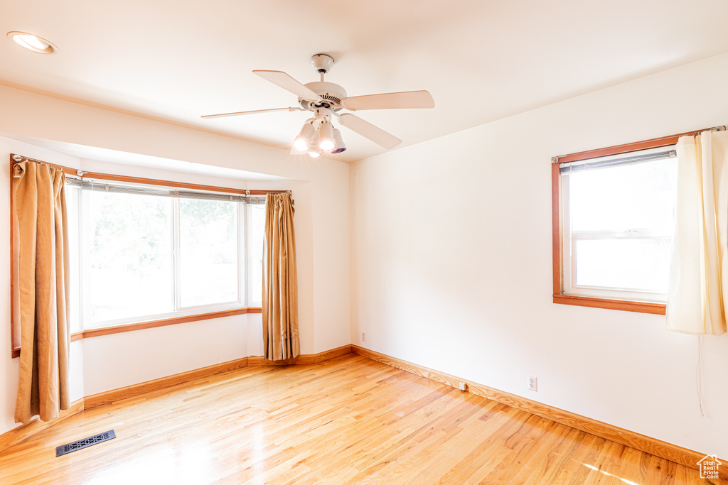 Unfurnished room with ceiling fan, light wood-type flooring, and a healthy amount of sunlight