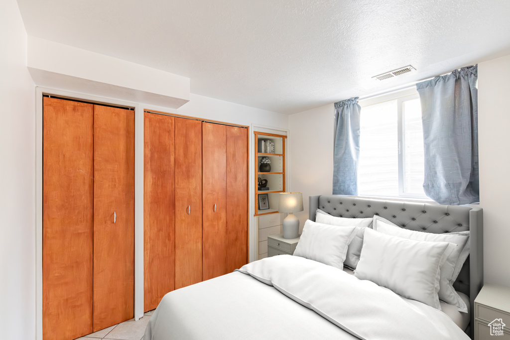 Bedroom with a textured ceiling and multiple closets