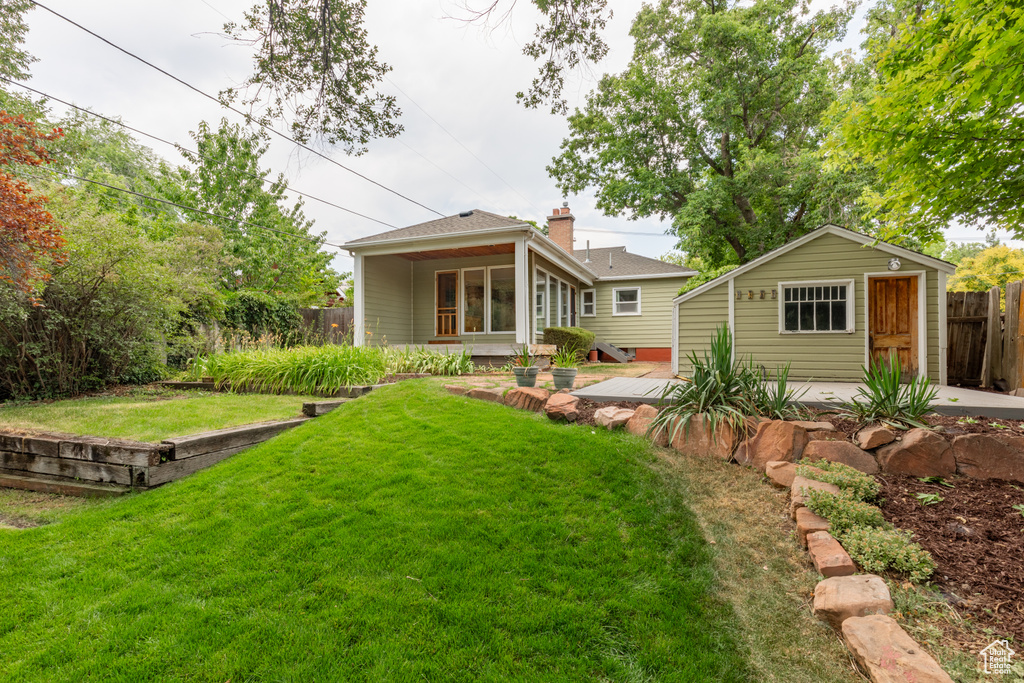 Back of house with an outbuilding, a lawn, and a deck