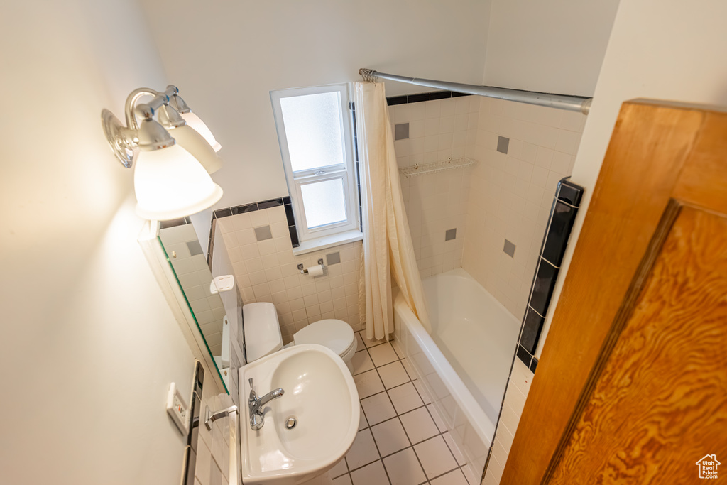 Full bathroom with shower / bath combo, tile walls, toilet, tile patterned floors, and sink