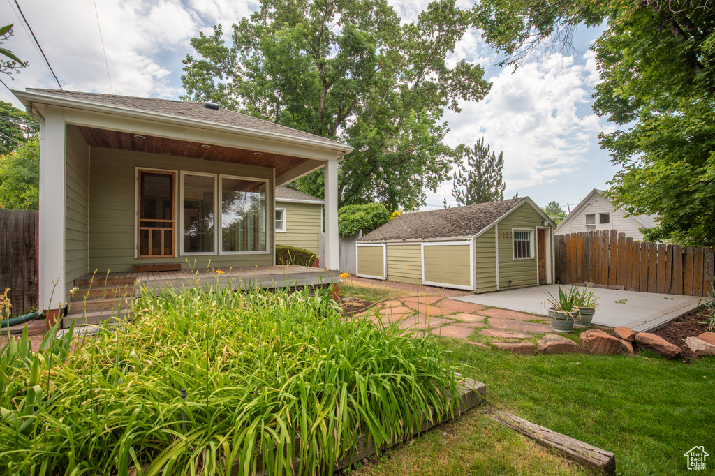 Back of property featuring a patio, a yard, and an outbuilding