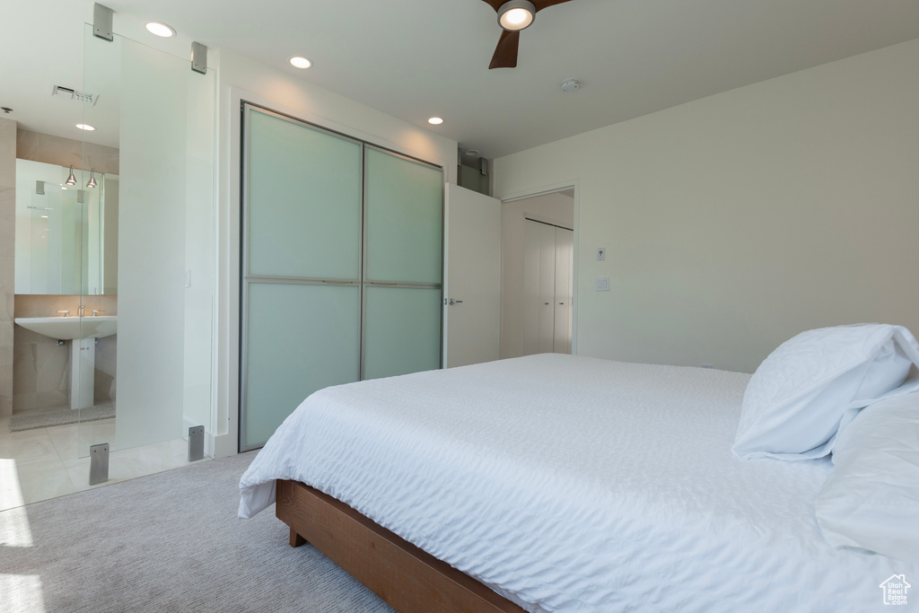 Bedroom featuring ceiling fan, ensuite bathroom, and light carpet