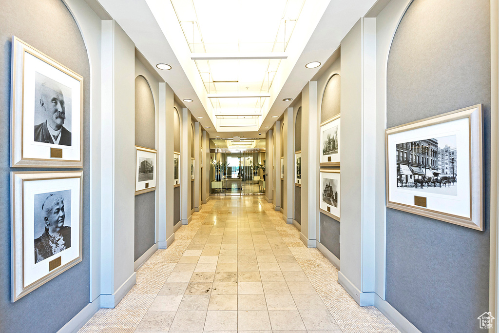 Corridor featuring light tile patterned flooring and a tray ceiling