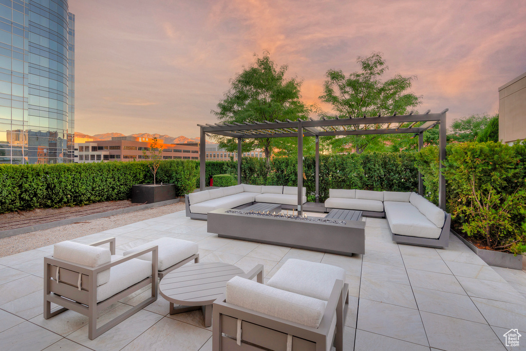 Patio terrace at dusk featuring a pergola and an outdoor living space with a fire pit