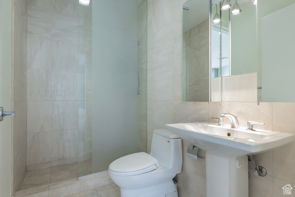 Bathroom featuring tile walls, backsplash, toilet, and tile patterned flooring