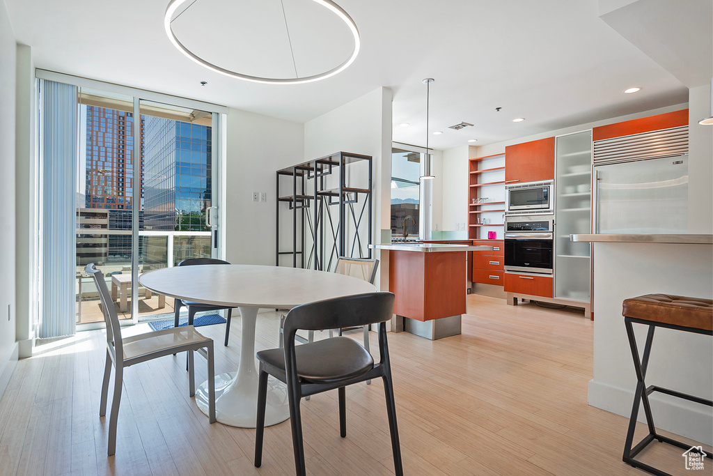 Dining room featuring light hardwood / wood-style flooring, sink, a wall of windows, and plenty of natural light