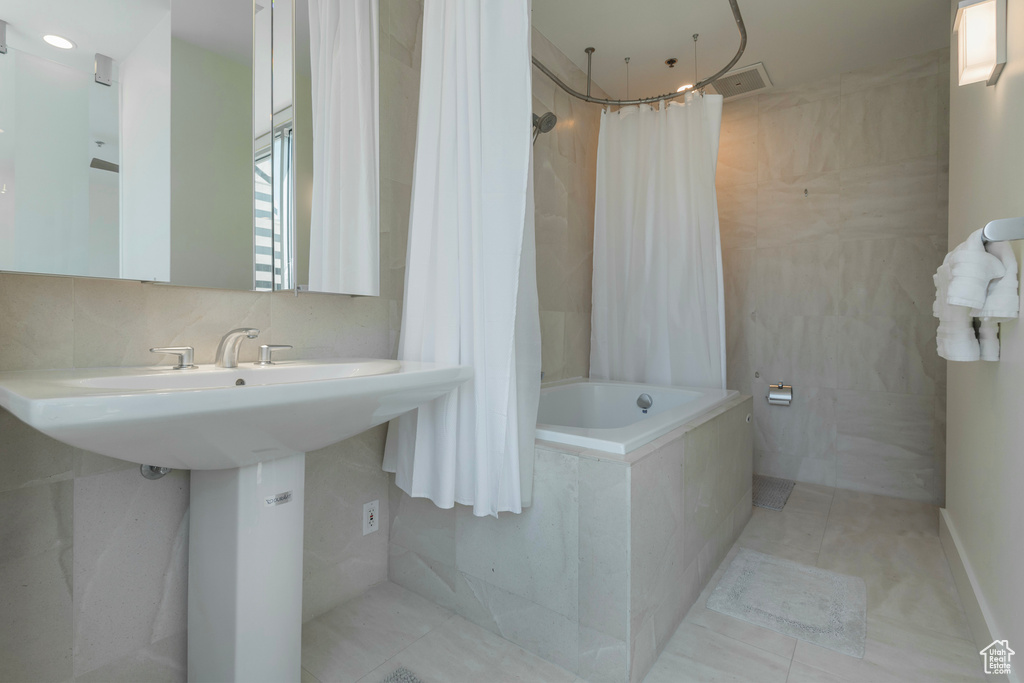 Bathroom with shower / tub combo with curtain, tile patterned floors, and tile walls