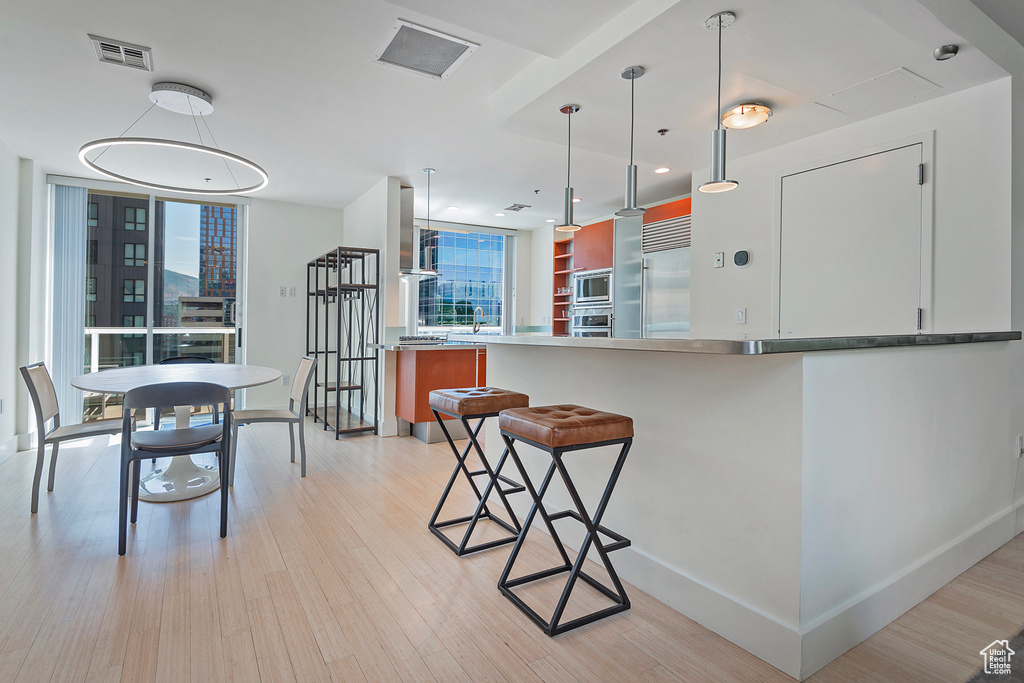 Kitchen with light wood-type flooring, built in appliances, and a kitchen bar