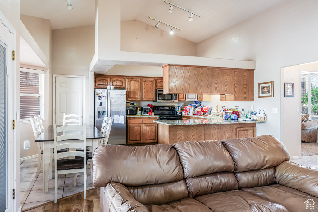 Kitchen featuring high vaulted ceiling, stainless steel appliances, and rail lighting