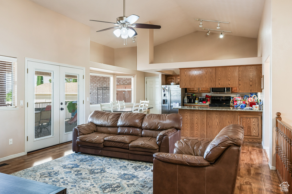 Living room featuring ceiling fan, french doors, rail lighting, high vaulted ceiling, and wood-type flooring