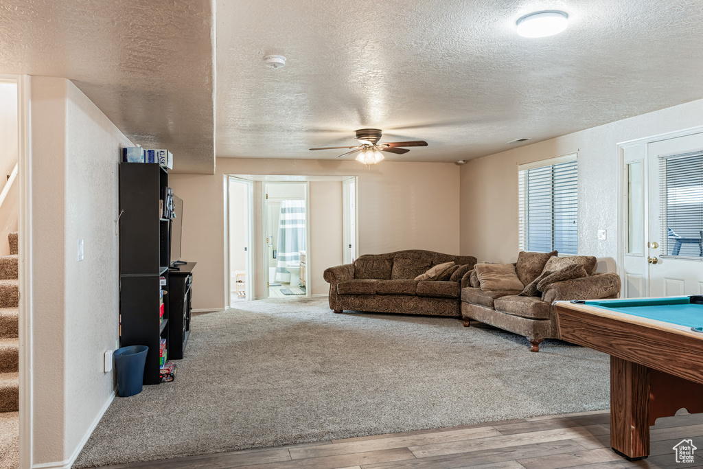 Living room featuring a textured ceiling, pool table, light wood-type flooring, and ceiling fan