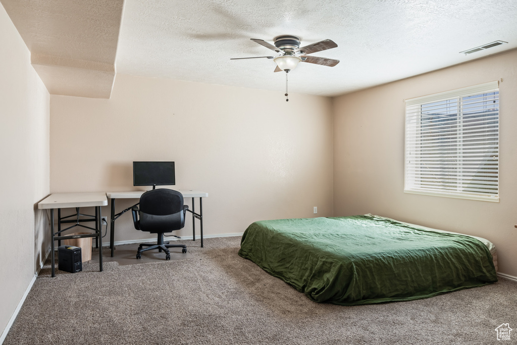 Bedroom with ceiling fan, a textured ceiling, and carpet floors