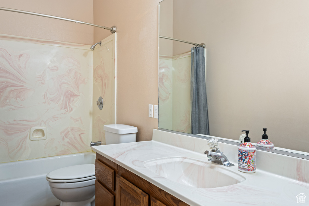 Full bathroom featuring shower / bathtub combination with curtain, toilet, and vanity